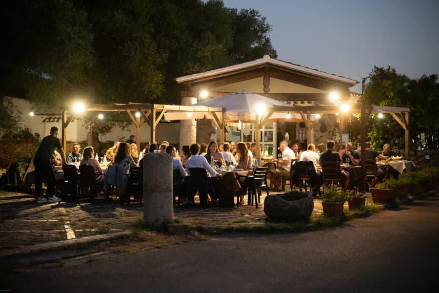 A long evening table outdoors, lit beneath the pergola