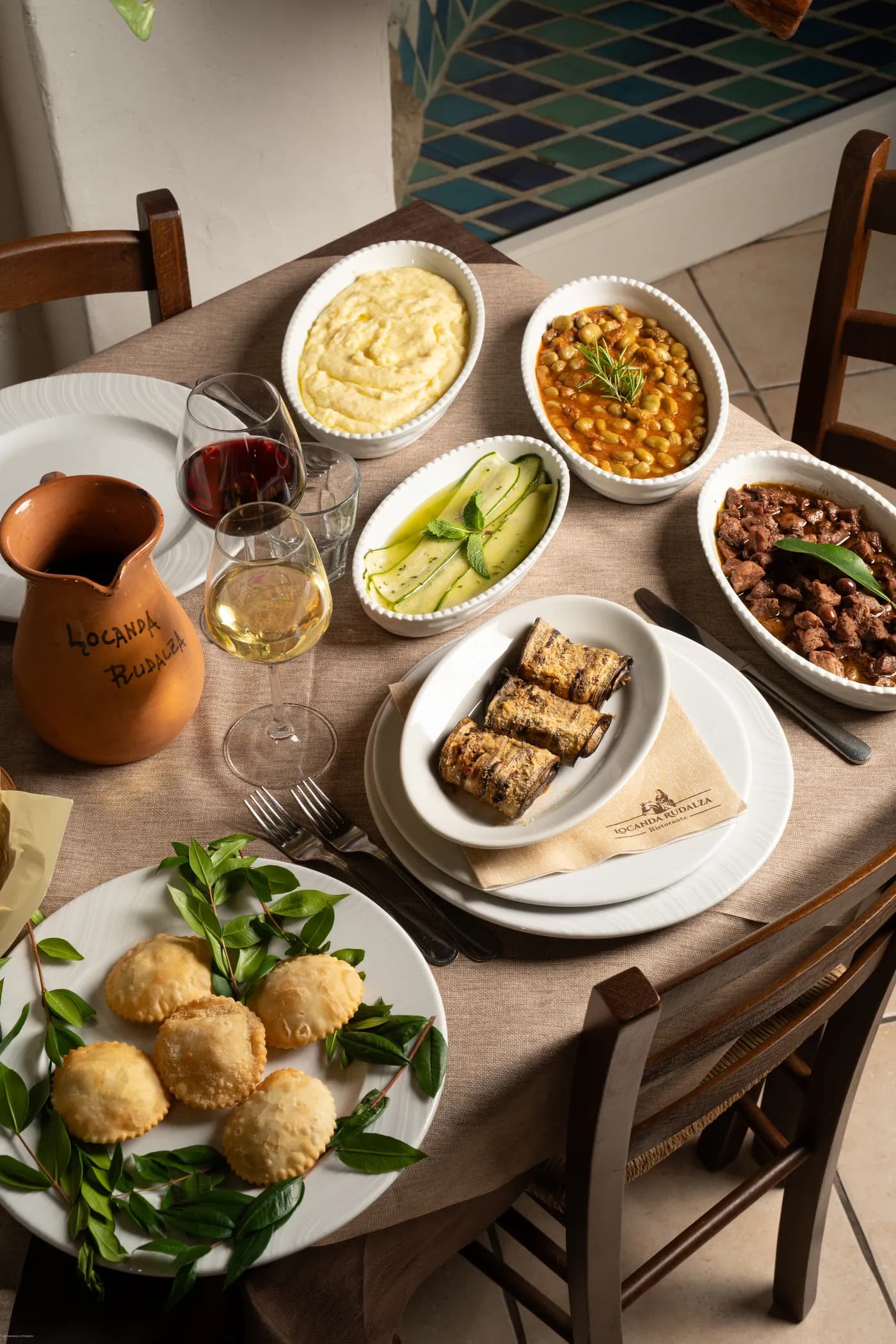 A table laden with traditional Sardinian dishes, with a carafe and wine