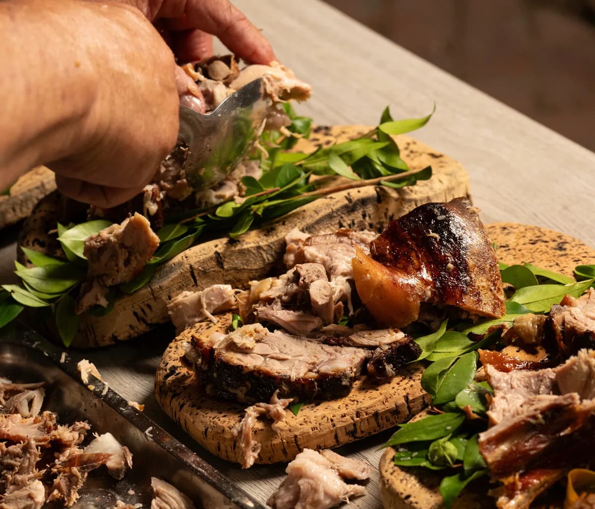 Roasted Sardinian porcetto, carved and served on a board with fresh herbs