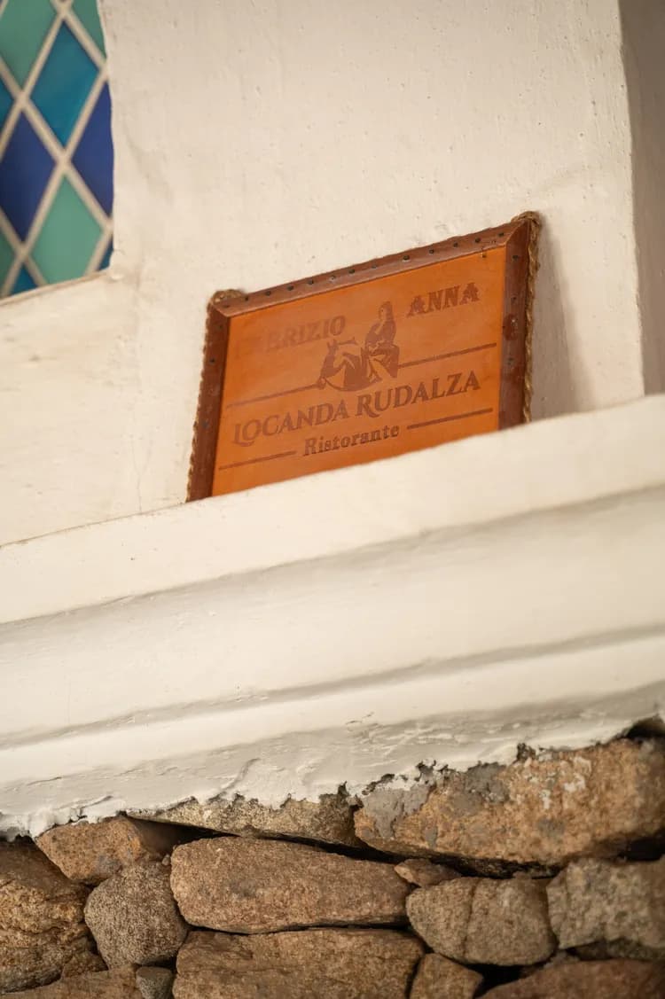 Wooden Locanda Rudalza sign resting on a stone sill